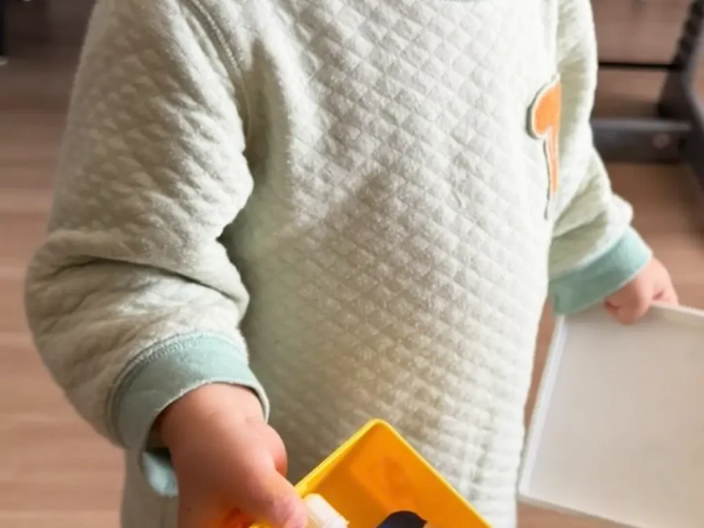 お弁当箱を差し出す2歳児の写真