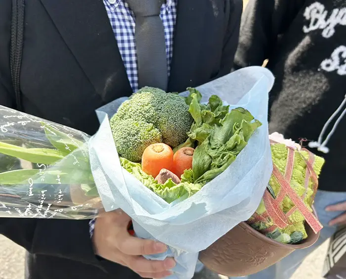 野菜のブーケを持つ高校生の写真