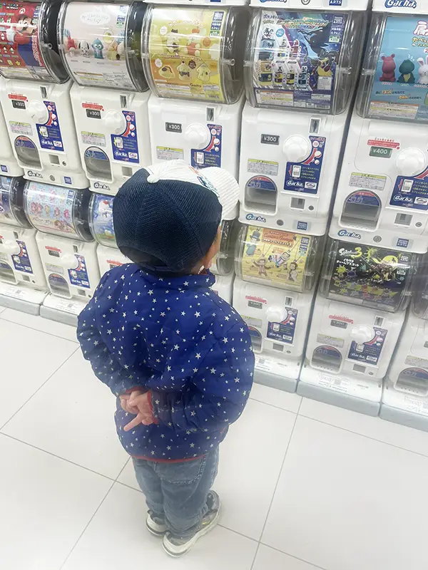 カプセルトイを見つめる4歳児の写真