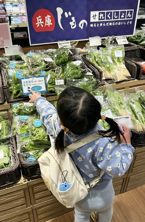 スーパーの野菜売り場にいる2歳児の写真