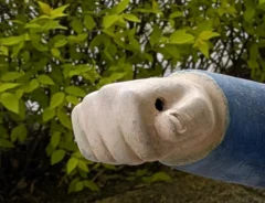 片手を前に突き出した、庭に置かれた小人の置物の写真
