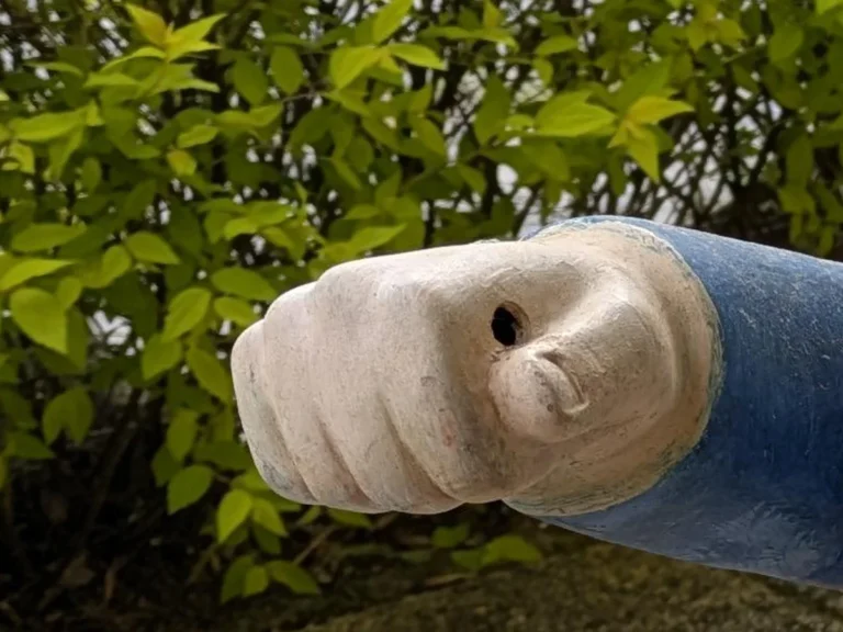 片手を前に突き出した、庭に置かれた小人の置物の写真